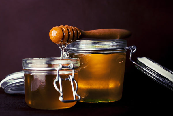 two jars of honey and a honey dipper